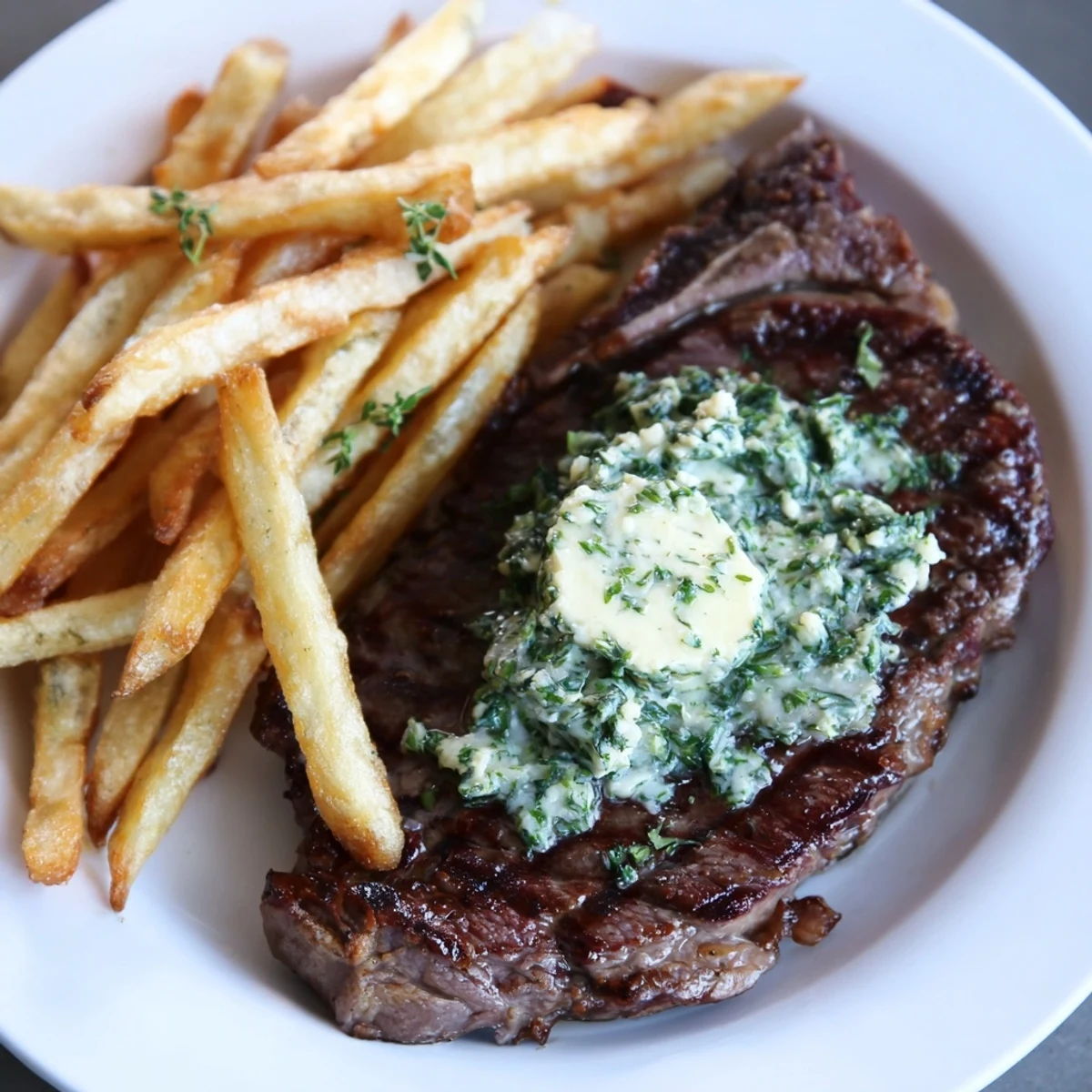 Juicy steak & fries topped with garlic butter: a flavorful, sizzling steakhouse classic, perfect!