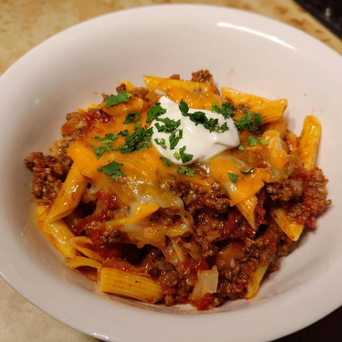 Enjoy this comforting bowl of Easy Beef Enchilada Pasta garnished with fresh cilantro and sour cream.