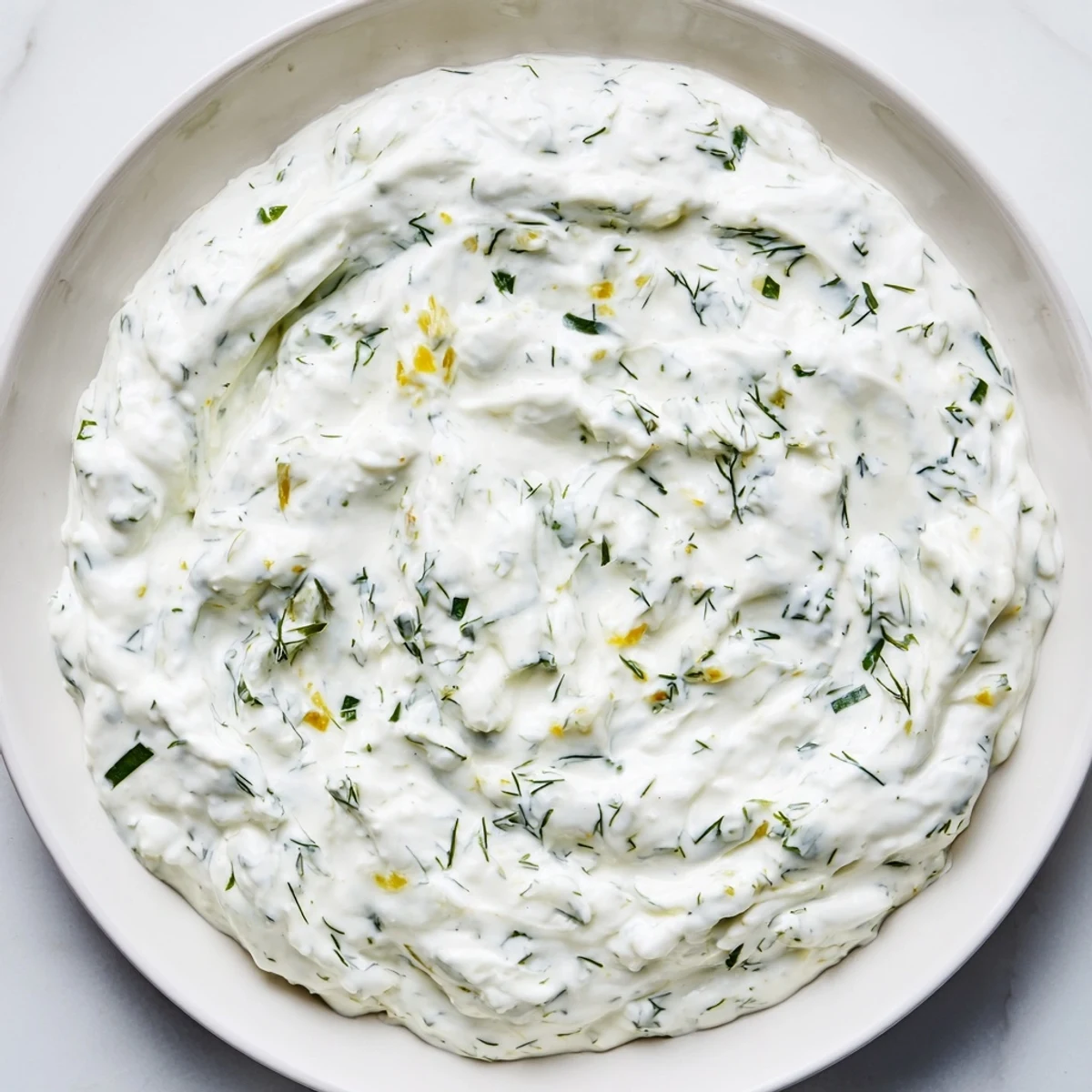 Creamy Greek Yogurt Ranch Dip, studded with vibrant green herbs, and ready to be scooped up.