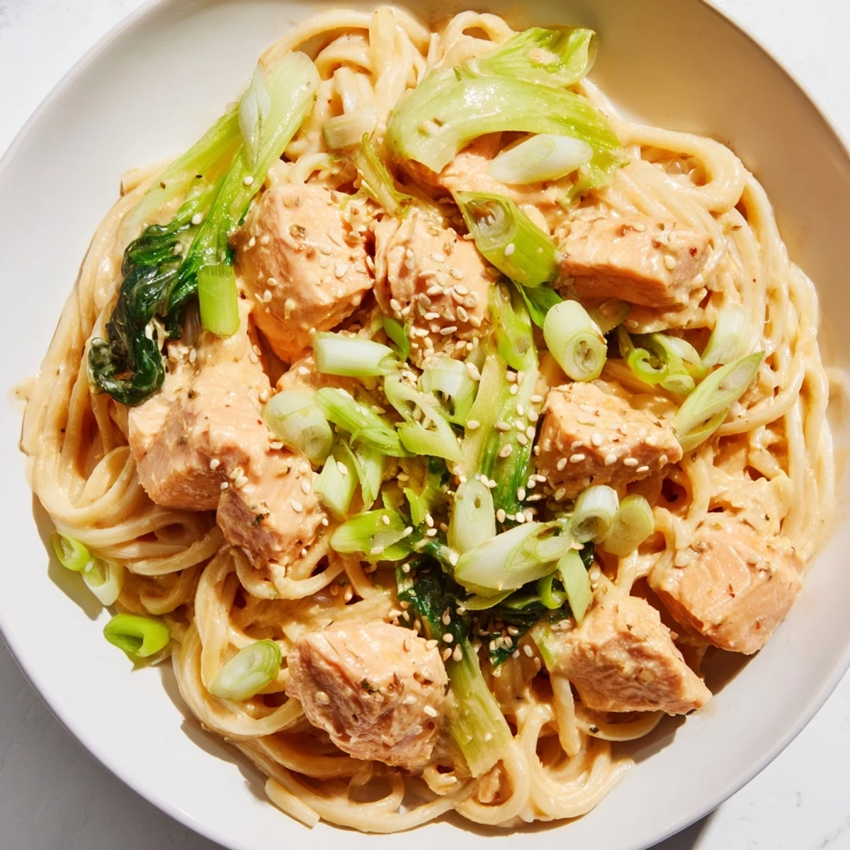 A close-up shot of delicious Miso Butter Salmon Pasta, garnished with fresh scallions and sesame seeds.