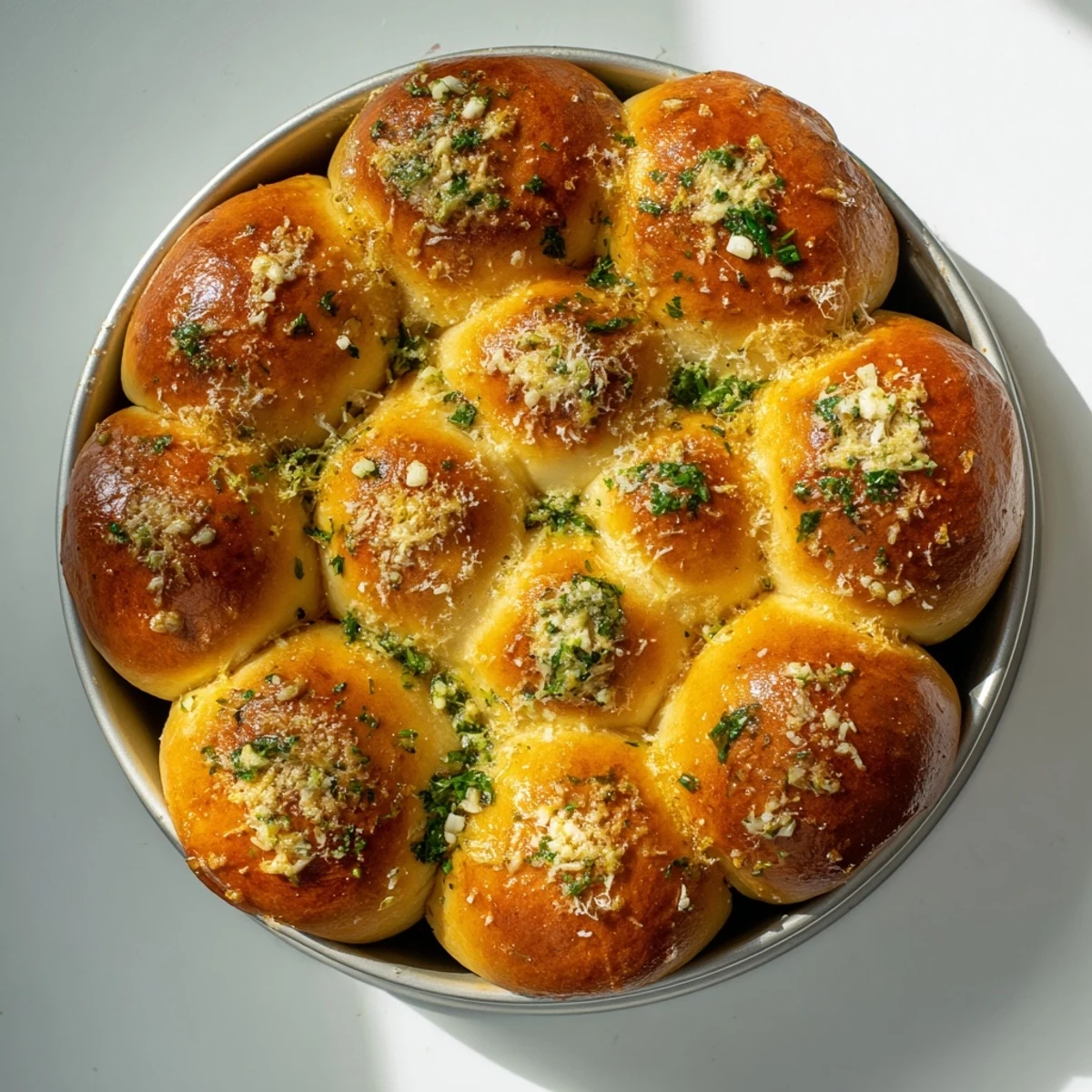 A close-up of a cheesy Garlic Butter Bread Pull-Apart, with melted butter and minced garlic glistening on soft rolls.  