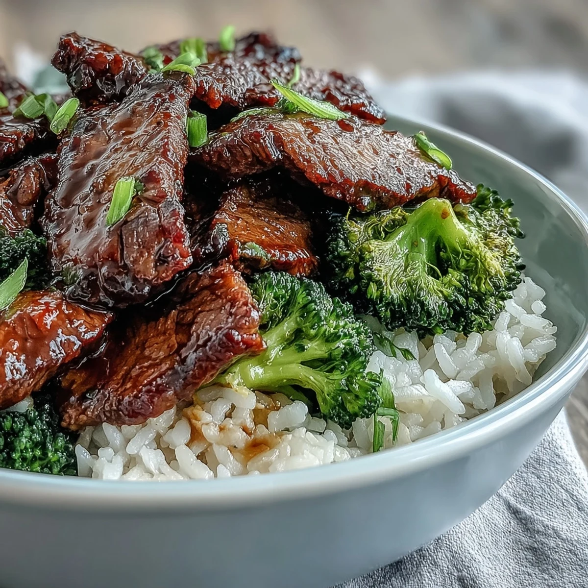 A steaming bowl of Beef and Broccoli Bowl features fluffy rice topped with tender beef strips and crisp green broccoli.