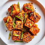 Close-up of freshly glazed Honey Sriracha Tofu Nuggets with sesame seeds and green onions on top.