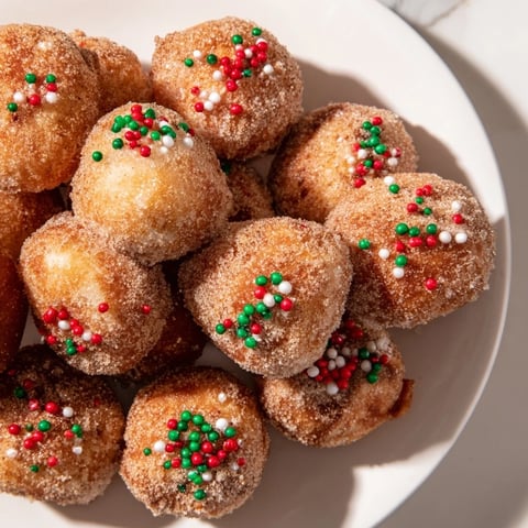 Air fryer Christmas donut holes: golden, sugared bites dusted with holiday sprinkles, ready to enjoy.