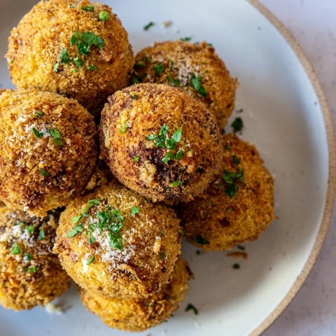 Golden-brown Creamy Chicken & Rice Arancini Balls ready to eat, served with a dipping sauce.
