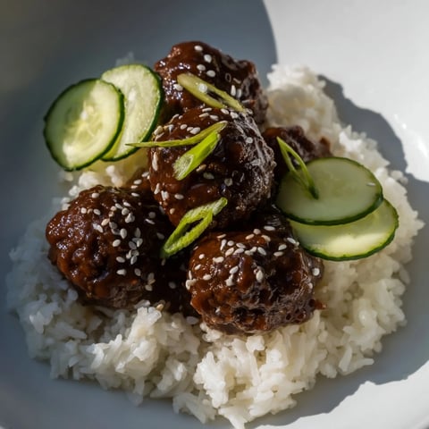 Steaming teriyaki meatball bowls featuring glistening meatballs with a savory glaze, served attractively.