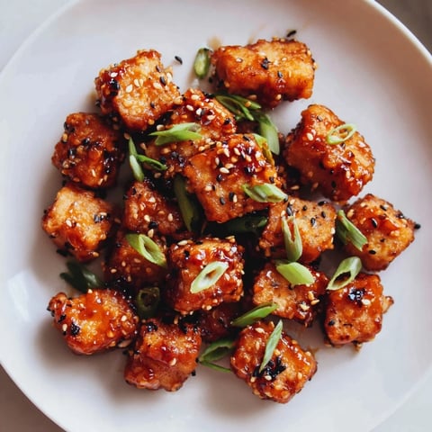 Golden crispy Honey Sriracha Tofu Nuggets, glistening with a sweet and spicy sauce, ready to eat.