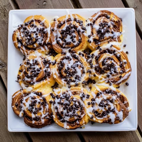 Freshly baked Nutella chocolate chip rolls with gooey melted chocolate filling on a rustic wooden board.