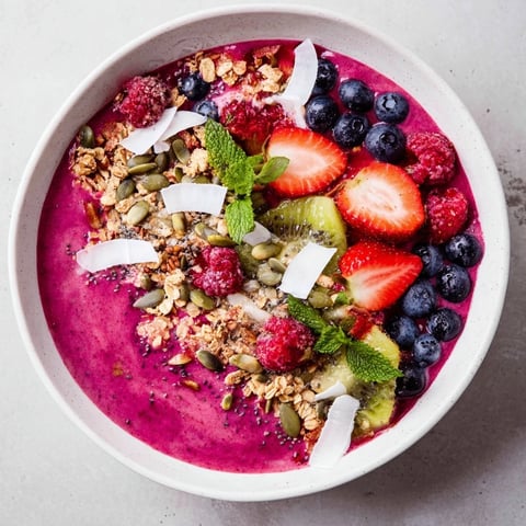 A vibrant Beet and Berry Smoothie Bowl topped with granola and fresh fruit for breakfast.