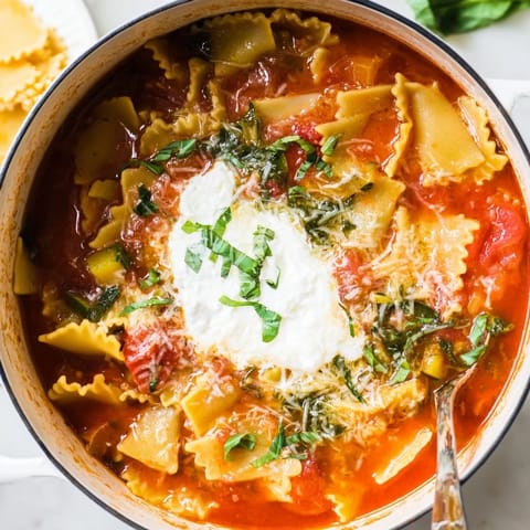 Delicious veggie-packed one-pot lasagna soup, garnished with fresh basil and melted cheese.  