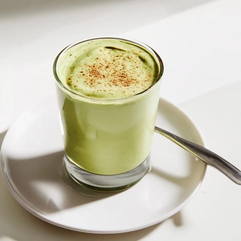Imagine thick, green Matcha Eggnog Collagen Breakfast Smoothie swirled in a glass, accented with nutmeg.