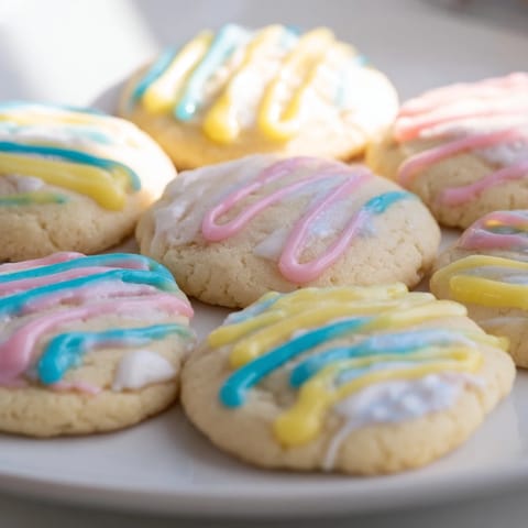 Plate of perfectly frosted sugar cookies boasting a vibrant icing drizzle, ready for a sweet bite.