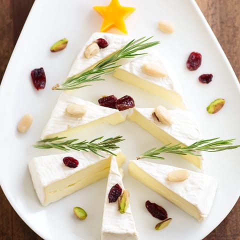 Elegant Brie Triangle Cheese Tree ready to serve, layered with sprigs of rosemary and tasty crackers beside it.