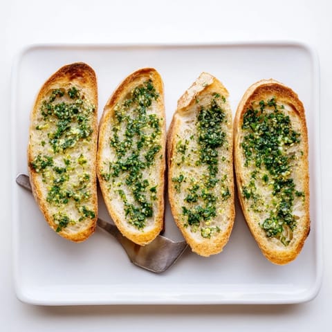 A close-up of warm Herb Butter Toast, with crusty sourdough and finely chopped parsley and chives visible.  