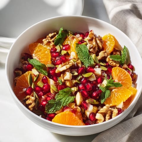 A close-up of the Pomegranate and Walnut Salad highlights juicy pomegranate arils and crunchy walnuts glistening with lemon dressing.  