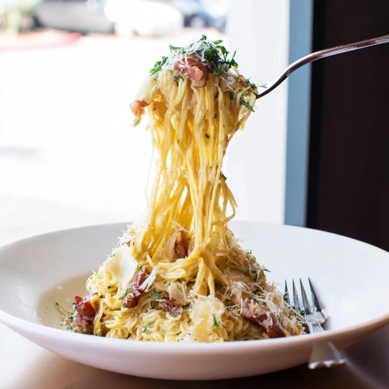 A close-up of delicious Carbonara Ramen Fusion: cheese-covered noodles with crispy bacon.