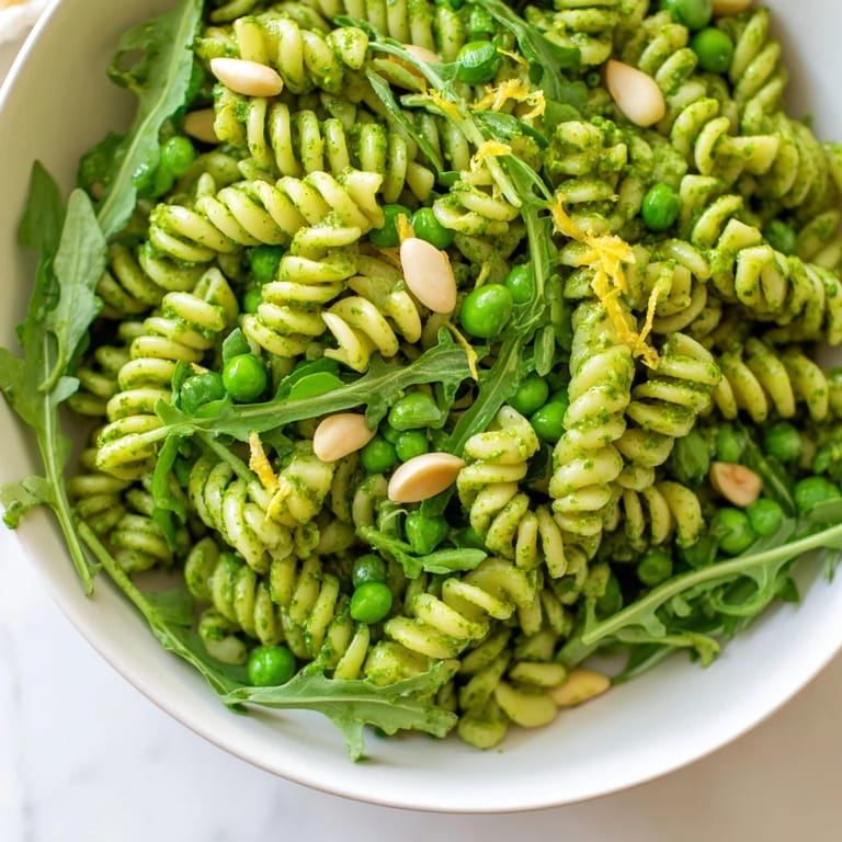 Close-up of Spring Green Pesto Pasta Salad tossed with homemade basil pesto, toasted pine nuts, and crumbled feta cheese.  