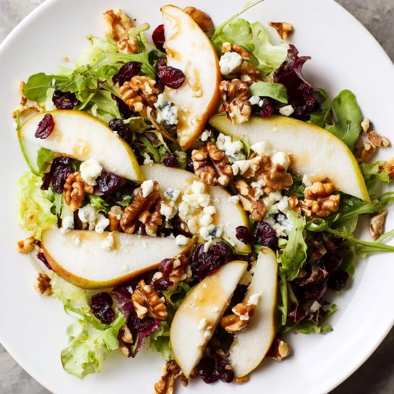 Tangy Gorgonzola and sweet pears top this vibrant salad, with toasted walnuts and cranberries on mixed greens.