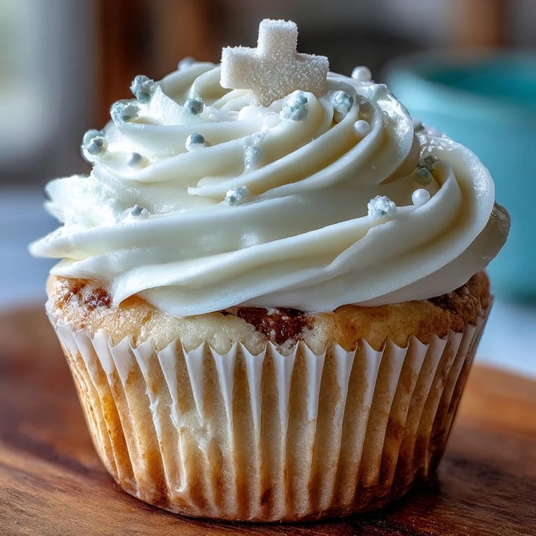Beautiful vanilla cupcakes decorated with smooth frosting and delicate fondant cross toppers, great for festive occasions.