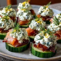 Smoked salmon cucumber bites with creamy herbed cheese on crisp cucumber rounds.  